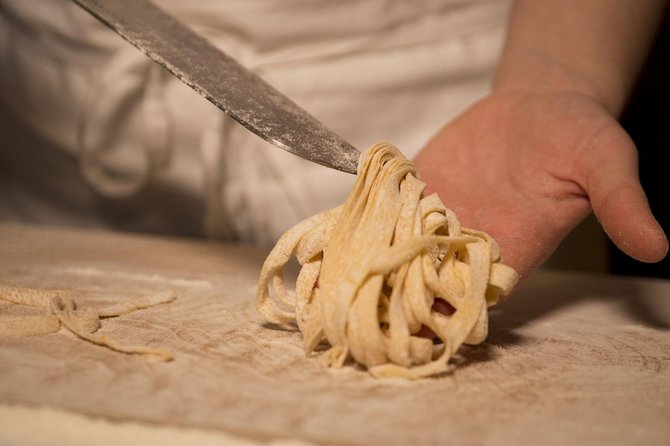 Hands rolling fresh fettuccine on a floured board